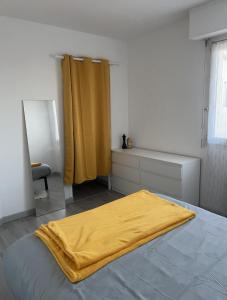 a bedroom with a bed with a yellow blanket on it at Langueux Apartment in Langueux