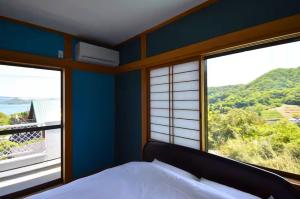 a bedroom with a bed and two large windows at Sunrise Resort Aji in Takamatsu