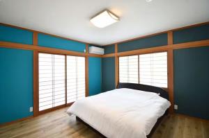 a bedroom with blue walls and a white bed at Sunrise Resort Aji in Takamatsu