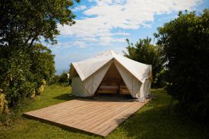 a canvas tent on a wooden deck in a field at HolaCamp Luarca in Luarca