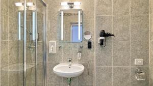 a bathroom with a sink and a glass shower at Schlossberg Hotel Wernigerode in Wernigerode +81 photos