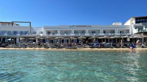 a hotel on the beach with chairs and people in the water at Acrogiali Beachfront Hotel Mykonos in Platis Gialos