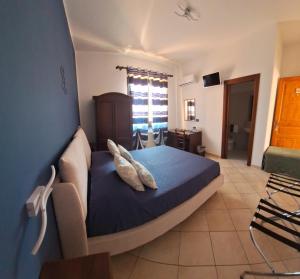 a bedroom with a blue bed with two pillows at Mariposa B&B in San Vito lo Capo