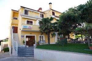 a yellow house with palm trees in front of it at Studio Apartman Rovinj in Rovinj