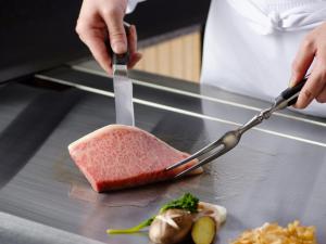 a person cutting a piece of food with a knife at Hotel New Otani Osaka in Osaka