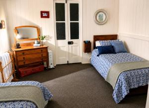 a bedroom with two beds and a mirror and a dresser at Dillons Cottage in Stanthorpe