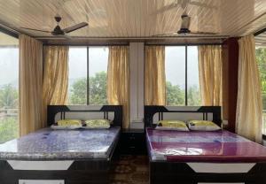 two beds in a room with two windows at Attra Farms in Karjat