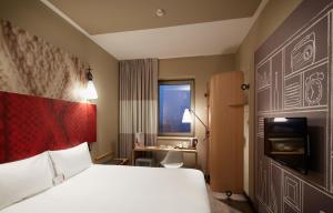 トゥズラにあるIbis Istanbul Tuzla Hotelの大きなベッドとデスクが備わるホテルルームです。