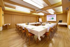 Landhotel Grüner Baum في Westendorf: قاعة اجتماعات مع طاولات وكراسي وشاشة
