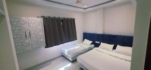 a bedroom with two beds and a blue headboard at Hotel Durga Palace in Ujjain +5 photos