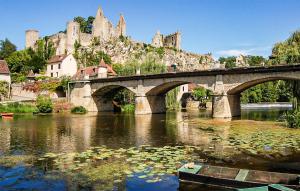 a bridge over a river with a castle in the background at Cottage À La Campagne in Mérigny +13 photos