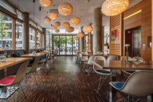 ein Restaurant mit Tischen und Stühlen und großen Fenstern in der Unterkunft Grimm's Berlin Mitte in Berlin