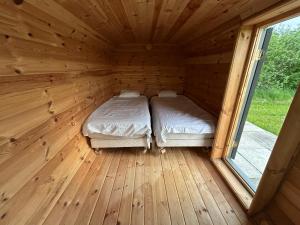 two beds in a wooden room with a window at Atpūtas vieta Friči in Līguti