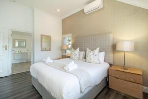a bedroom with a large white bed with a lamp on a table at Winelands Golf Lodges 3 in Stellenbosch +56 photos