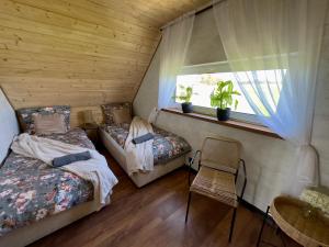 two beds in a room with a window and a chair at Hulaj Dusza - dom nad stawem in Cisów +46 photos