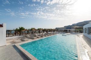 a swimming pool with lounge chairs in a resort at Sun Beach Lindos in Lartos