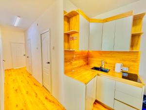 a kitchen with white cabinets and a wooden floor at Yura Hostel in Darhan