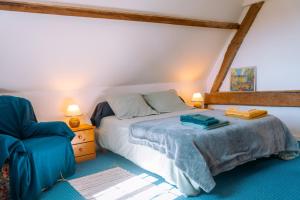 a bedroom with a bed and a blue chair at Gîte de caractère - La Grangette in Saint-Julien-le-Faucon