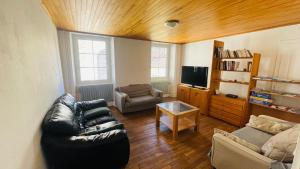 a living room with a leather couch and a tv at Gîte du canal in Lutzelbourg