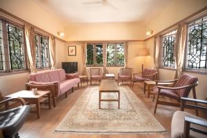 a living room with chairs and tables and windows at Sinna Dorai's Moulmein House in Vālpārai +5 photos
