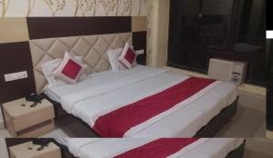 a bedroom with a large bed with red and white sheets at Hotel Travora Suits -Lalquila in Bhubaneshwar