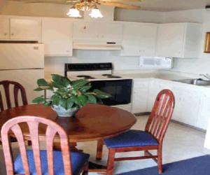 a kitchen with a wooden table and chairs and a kitchen with a sink at Coral Reef Inn & Condo Suites in Alameda