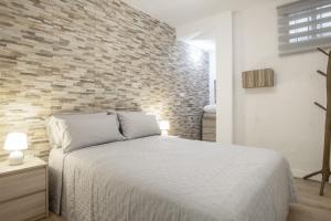a bedroom with a bed and a brick wall at Vejer de la frontera 100 pza España in Vejer de la Frontera