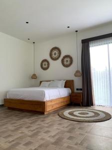 a bedroom with a bed and a large window at Cozzy Sagas House Tabanan in Perean