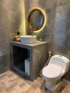 a bathroom with a toilet and a sink and a mirror at Cozzy Sagas House Tabanan in Perean