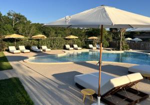 ein Pool mit Liegestühlen und einem Sonnenschirm daneben in der Unterkunft Sainte Raphine in Fargues-Saint-Hilaire