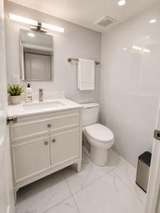 a white bathroom with a sink and a toilet at Parkside luxury suite and EV station in Jenkintown