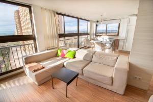 a living room with a white couch and large windows at Mediterranean Front Beach Apartment in El Puig