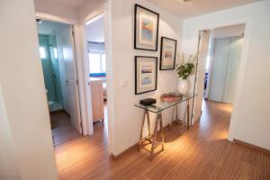 a hallway with a glass table and framed pictures on the wall at Mediterranean Front Beach Apartment in El Puig