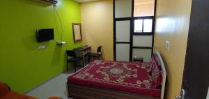 a room with a bed and a desk and green walls at Hotel Anmol&Rooms in Gothaj