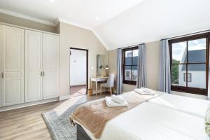 a white bedroom with a large bed and a desk at Winelands Golf Lodges 12 in Stellenbosch