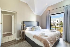 a bedroom with a large bed and a balcony at Winelands Golf Lodges 12 in Stellenbosch