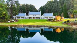 a house with a lake in front of it at Private Manor Estate Fly Fishing Sleeps 18 in Dullstroom