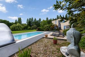 a yard with a pool and a statue next to a house at Gite Douceur de vivre in Saint-Avaugourd-des-Landes