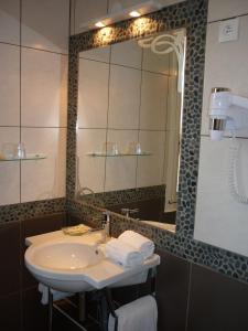 a bathroom with a sink and a large mirror at Adonis Sanary Grand Hôtel des Bains in Sanary-sur-Mer