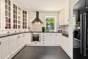 a kitchen with white cabinets and a black refrigerator at Beach House With Multiple Terraces In Holmsbu in Holmsbu
