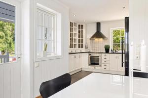 a kitchen with white cabinets and a black chair at Beach House With Multiple Terraces In Holmsbu in Holmsbu