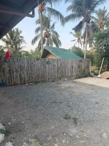 a wooden fence with a building with a green roof at Itawis Resort - Nature Chalet in Silang