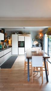 a kitchen with a wooden table and white cabinets at Chambre avec Piscine Maison EtxeCosy in Bidart