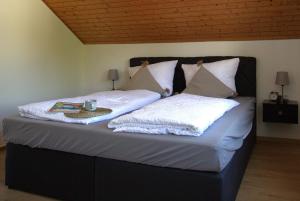 a bed with two pillows and a book on it at Rose in Überlingen