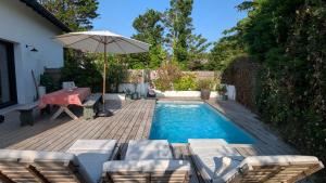 a swimming pool with a table and an umbrella at Chambre avec Piscine Maison EtxeCosy in Bidart