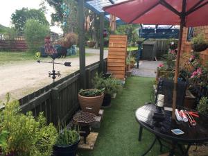 a garden with a table and an umbrella and some plants at Sleeps 2 includes breakfast in Garve