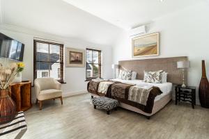 a bedroom with a bed and a chair and windows at Winelands Golf Lodges 14 in Stellenbosch