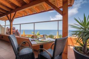 een patio met een tafel en stoelen en de oceaan bij Hotel Alpino Atlantico Ayurveda Cure Centre - Adults Only in Caniço