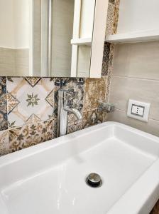 a white sink in a bathroom with tiles on the wall at Sole E Mare in Marina di Fuscaldo +59 photos