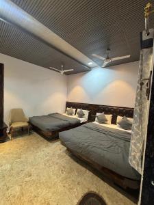 a bedroom with two beds and a chair at Meghdoot New Resort in Matheran +45 photos